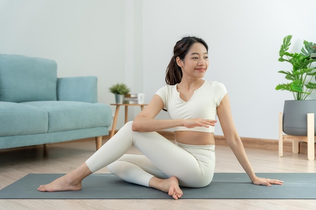 Donna magra che pratica yoga nella stanza del suo appartamento o casa donna asiatica che fa esercizi al mattino equilibrio meditazione rilassamento calma buona salute felice rilassamento stile di vita sano dieta magra