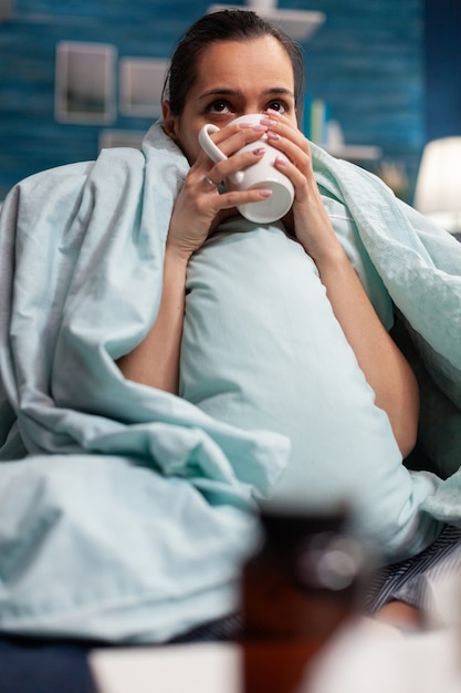 Donna malata a casa che riposa con una tazza di tè