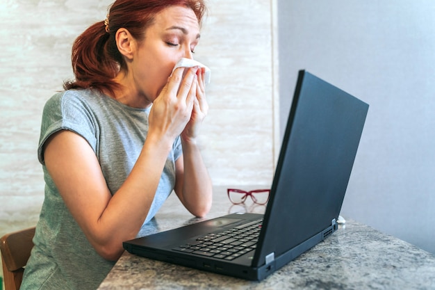 Donna malata che si siede allo scrittorio con il computer portatile dal Ministero degli Interni