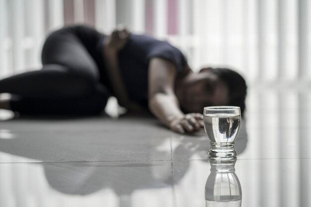 Donna malata che striscia verso un bicchiere d'acqua