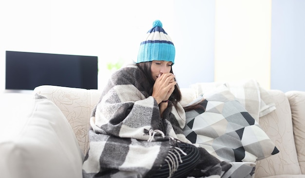 Donna malata con il cappello seduta sul divano