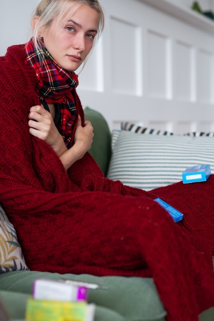 Donna malata con una brutta sensazione avvolta in una coperta e sofferente.