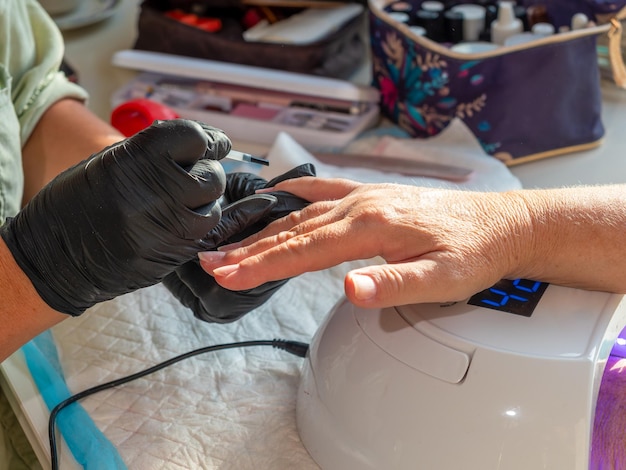 Donna manicure che applica olio alla cuticola dopo aver rimosso il vecchio smalto per la vernice permanente per unghie