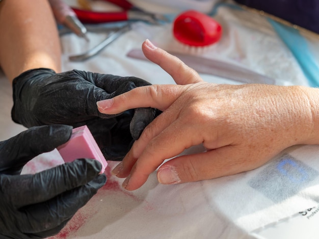 Donna manicure che usa la spugna da lucidatura per rimuovere il vecchio lucido per la vernice permanente per unghie