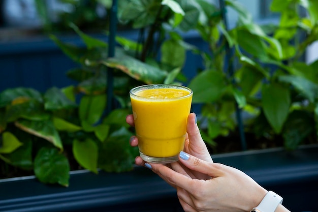 Donna mano azienda vasetto di vetro di succo d'arancia succo fresco su sfondo blu Bevanda sana