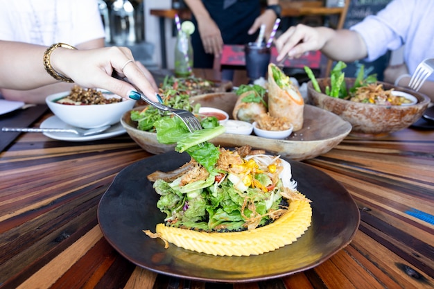 Donna mano con forchetta mangiare insalata di verdure con gli amici Cocept sano mangiare pulito.