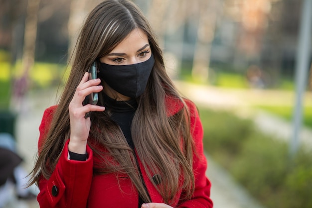 Donna mascherata che parla al telefono concetto di comunicazione covid e coronavirus