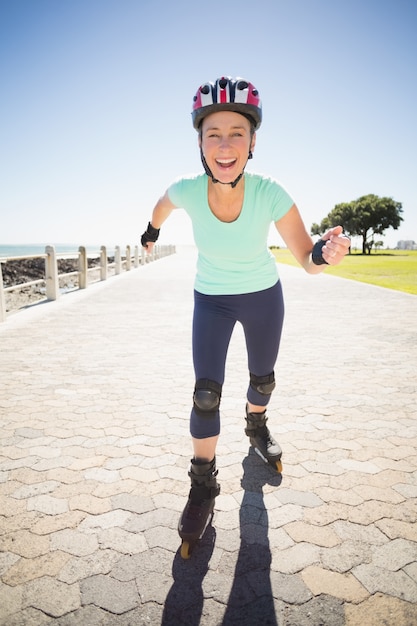 Donna matura adatta che rollerblading sul pilastro