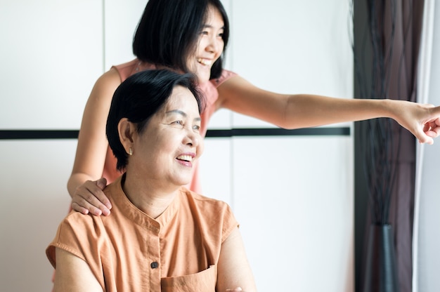 Donna matura asiatica felice con la figlia che si prende cura e supporto a casa, mamma anziana felice di mezza età, concetto di assicurazione senior
