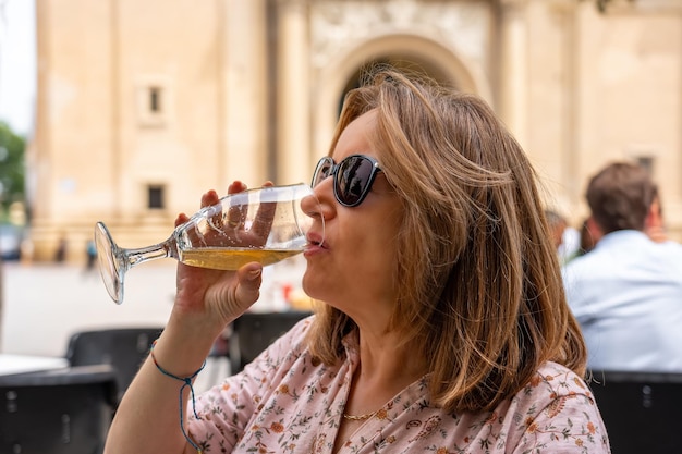 Donna matura avente una birra su una terrazza di un bar di strada Zaragoza Spagna