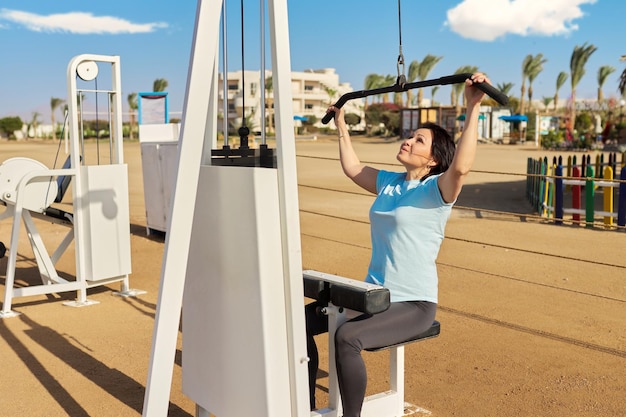 Donna matura che fa esercizi sportivi su simulatori all'aperto