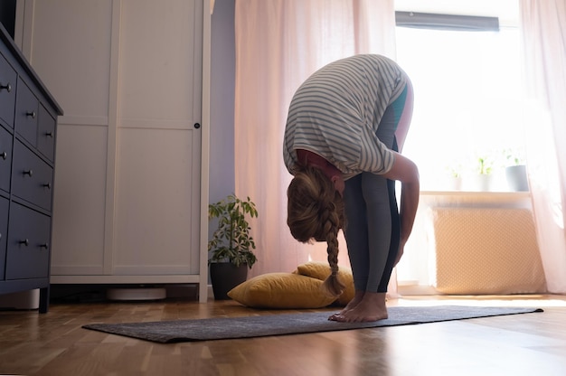 Donna matura che fa stretching a casa Uttanasana posa yoga