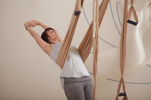 Donna matura che fa yoga della mosca allo studio di sport