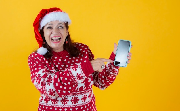 Donna matura che indica lo schermo dello smartphone, vestiti di natale