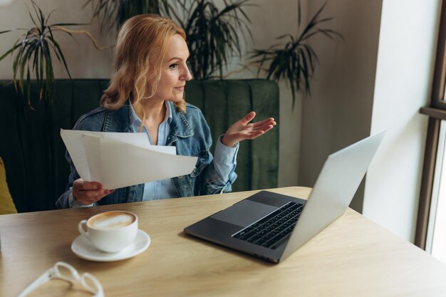 Donna matura che lavora al computer portatile nella caffetteria