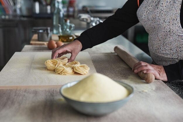 Donna matura che lavora all'interno di un pastificio facendo tagliatelle fresche