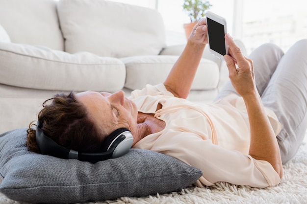 Donna matura che per mezzo del telefono mentre ascoltando le cuffie