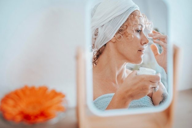 Donna matura che si applica la crema per il viso