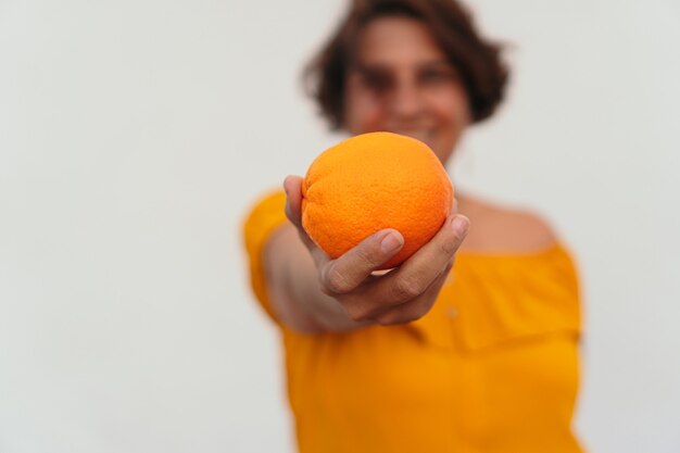 Donna matura che si gode la giornata di sole con l'arancia