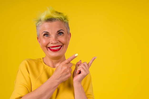 Donna matura con capelli tinti di giallo alla moda colorati e labbra rosse in abito caldo sfondo copia studio spase.forever young soul.