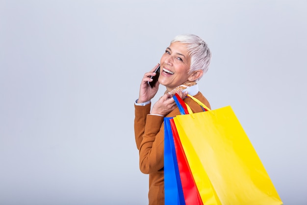 Donna matura con i sacchetti della spesa e il telefono cellulare