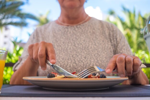 Donna matura con una sana colazione estiva classica frittelle americane banana kiwi miele di bacche fresche