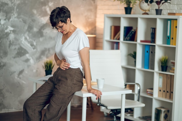 Donna matura dai capelli corti che soffre di dolori allo stomaco