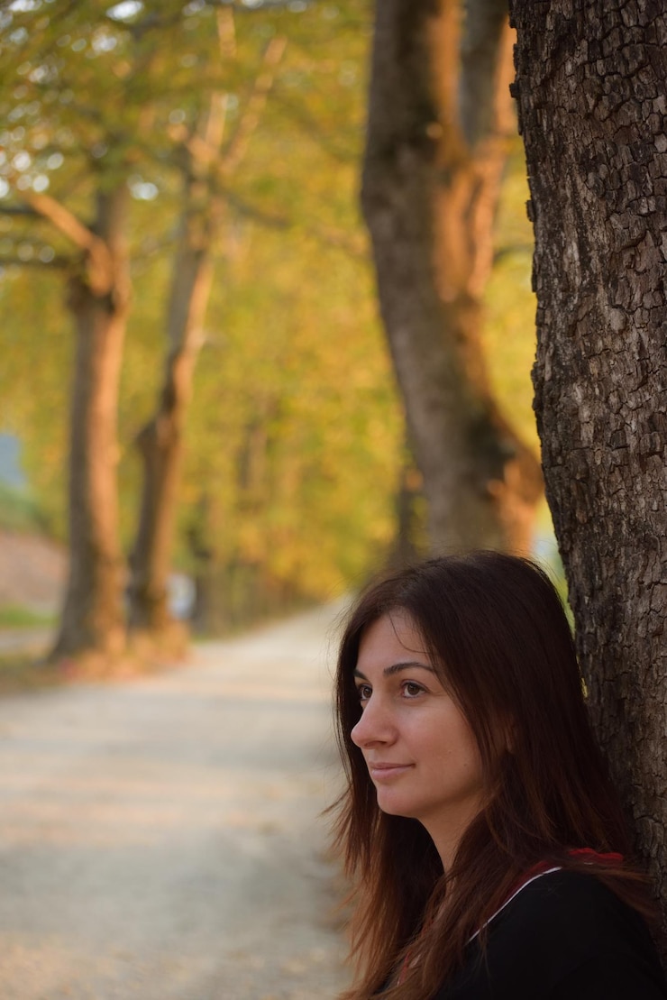 Foto donna matura e premurosa che guarda lontano dal tronco dell'albero.