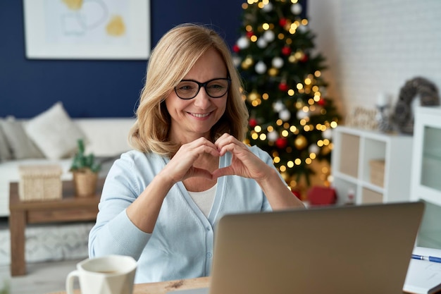 Donna matura felice che fa gesti durante una videoconferenza a casa