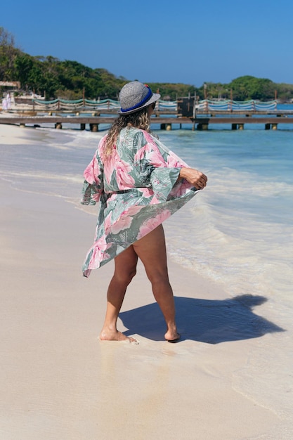 Donna matura in cappello che si gode la spiaggia