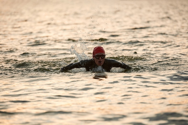 Donna matura in costume da bagno che si allena per nuotare nel lago all'aperto