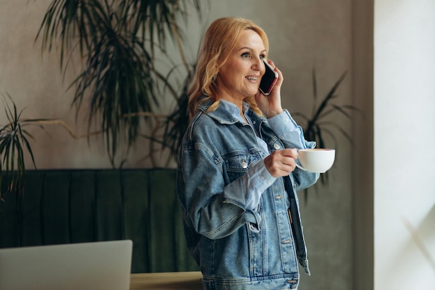 Donna matura parlare al telefono una bevanda caffè