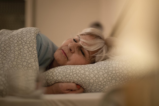 Donna matura sdraiata sul letto e dormendo di notte