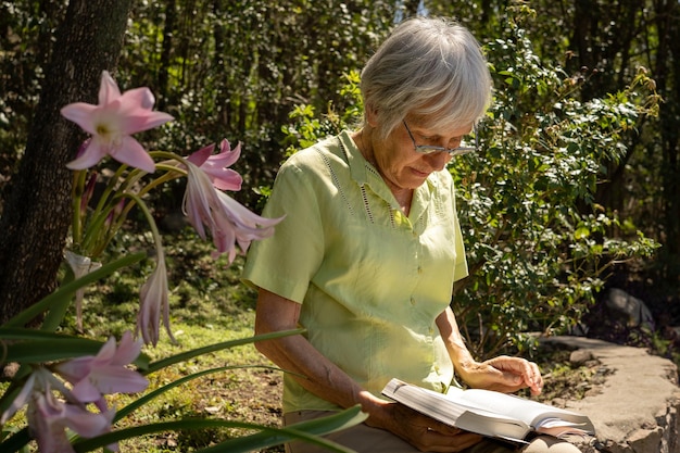 Donna matura seria che legge nel suo giardino