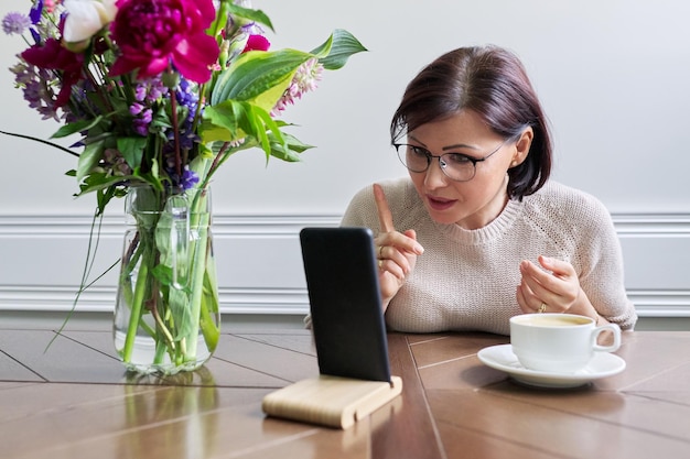 Donna matura seria che parla guardando lo schermo dello smartphone