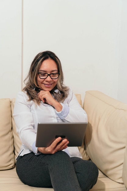 Donna matura sul divano utilizzando un tablet