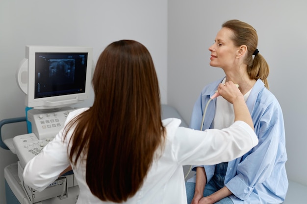 Donna medico che conduce l'ecografia della ghiandola tiroidea e dei linfonodi in primo piano. Visita medica completa presso la clinica moderna