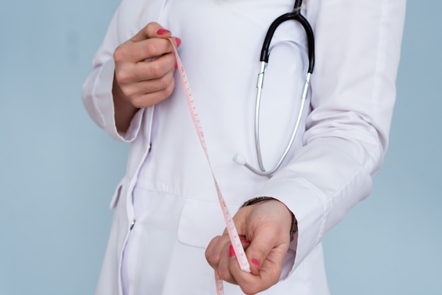 donna medico dietologa in camice bianco con stetoscopio e metro a nastro di misurazione centimetro