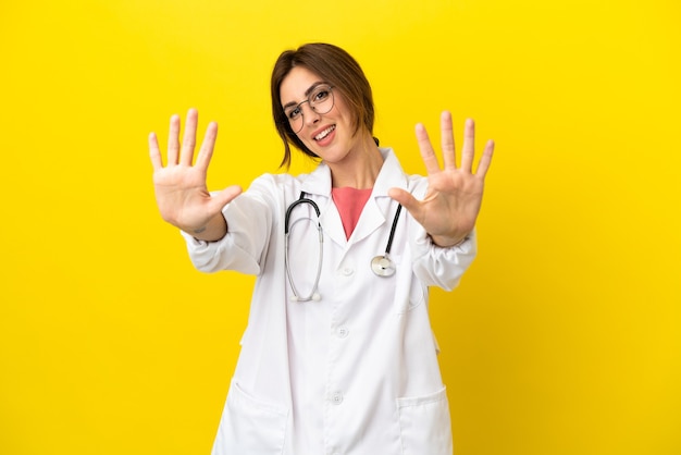 Donna medico isolata su sfondo giallo contando dieci con le dita