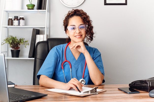 Donna medico ispanica con vista sull'ufficio della clinica che guarda l'obbiettivo