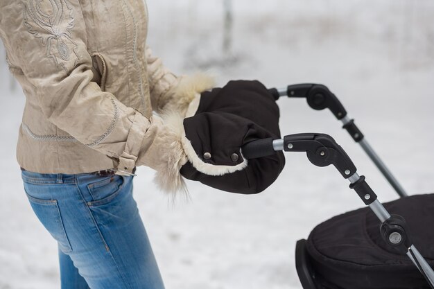 Donna mediorientale con aggancio per passeggino che va a fare una passeggiata in un parco durante un bel pomeriggio invernale