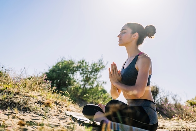 Donna meditando in una giornata di sole in spiaggia