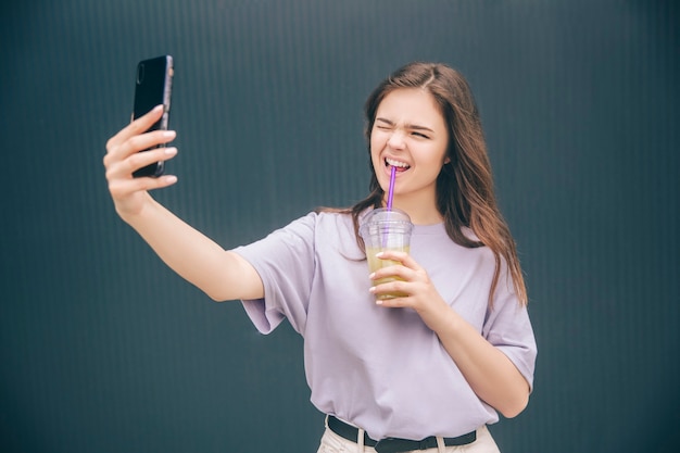 Donna meravigliosa che prende selfie e fa espressioni facciali divertenti