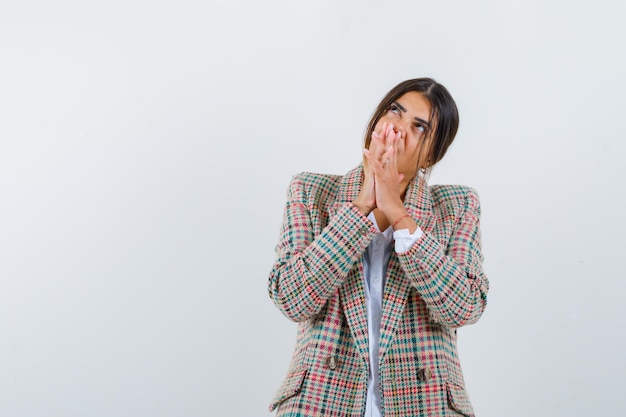 Donna messicana sognatrice in camicia bianca e giacca a quadri con le mani giunte e sognante isolata su sfondo bianco