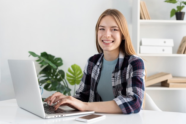 Donna moderna che lavora al suo computer portatile mentre guardando la telecamera