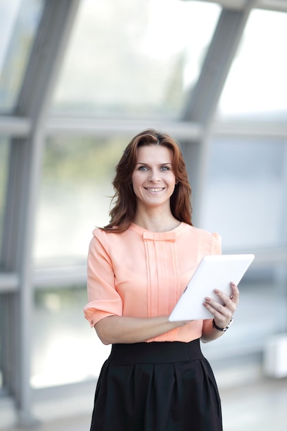 Donna moderna con tavoletta digitale in piedi in ufficio.persone e tecnologia