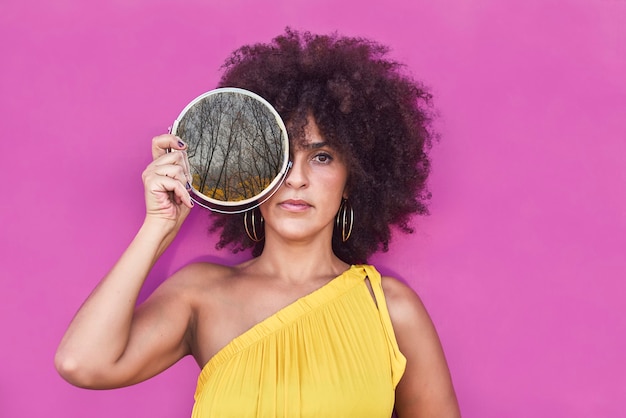 Donna mulatta dai capelli afro in un vestito giallo e sfondo viola.