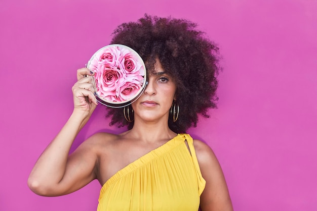 Donna mulatta dai capelli afro in un vestito giallo e sfondo viola.