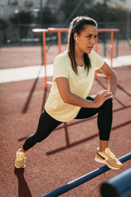 Donna muscolare motivata che si riscalda al campo sportivo