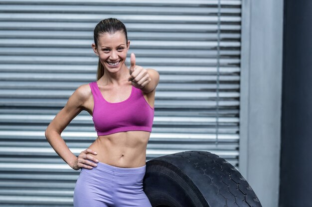 Donna muscolare sorridente che gesturing i pollici su